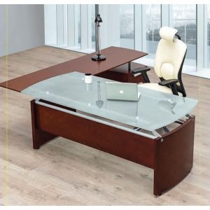 Escritorio moderno de cristal con base de madera y lámpara de escritorio en un ambiente de oficina.